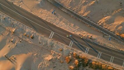 Aerial view cars driving along sandy trail path. Overhead desert offroad vehicle