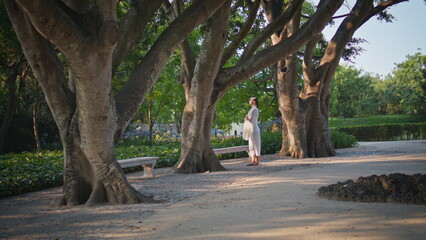 Romantic girl relaxing park wrapped in scarf. Dreamy woman standing under trees