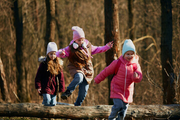 Pre-teens in winter outfit running, jumping energetically on dirt track outdoors. Environment...