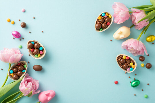 Sweet Easter collection concept. Overhead photo of cracked chocolate eggs, full of colorful candies, white chocolate bunny, sprinkles, fresh tulips on pastel blue background, space for text or advert