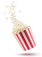 Popcorn flying from red and white striped container, isolated on white background.