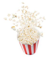 Popcorn flying from red and white striped container, isolated on white background.