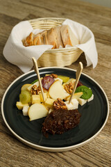 Various types of cheese on a plate with grapes and nut and bread