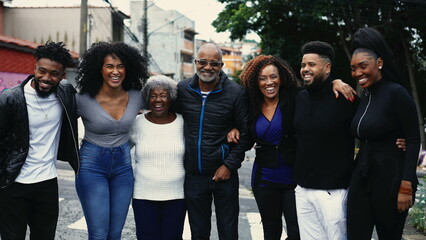 Group of Joyful Brazilian people smiling and laughing together standing in city street posing for camera. United Family of African descent embrace