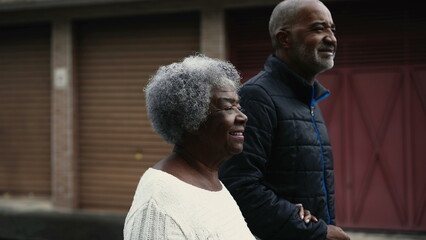 Joyful South American black Elderly gray hair lady in 80s walking in street with the help of her...