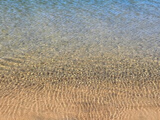 Shimmering abstract water pattern on a lake with sandy bottom