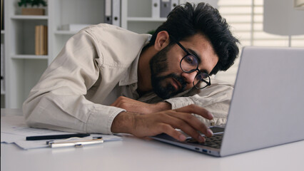 Lazy weary sleepy male manager tired exhausted Arabian Indian businessman employee working computer...