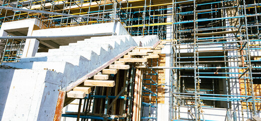 A construction site with scaffolding and a staircase. The staircase is made of wood and is being built