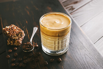 Dalgona coffee drink, cocktail with whipped instant coffee and milk in a glass on a wooden board...