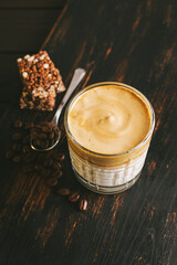 Dalgona coffee drink, cocktail with whipped instant coffee and milk in a glass on a wooden board with a healthy protein bar