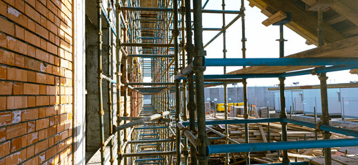 A construction site with scaffolding and a brick wall