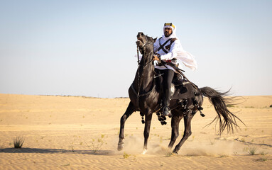 Rider in the desert of Saudi Arabia with his back stallion