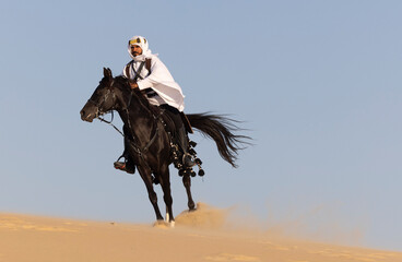 Rider in the desert of Saudi Arabia with his back stallion