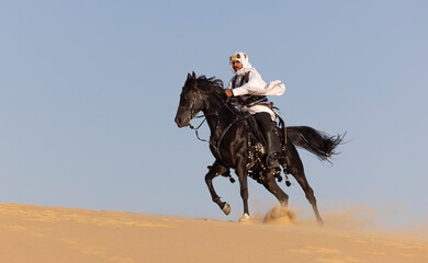 Rider in the desert of Saudi Arabia with his back stallion