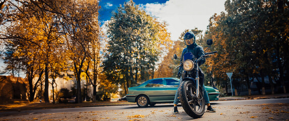 stylish male motorcyclist in a leather jacket and jeans with a classic city motorcycle