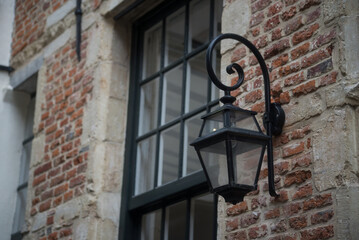 closeup of metallic old street lamp on brick wall facade in the street - 753759714