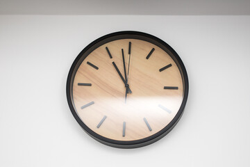 Office wall clock in the interior. Large clock on the wall with a wooden dial and black hands.