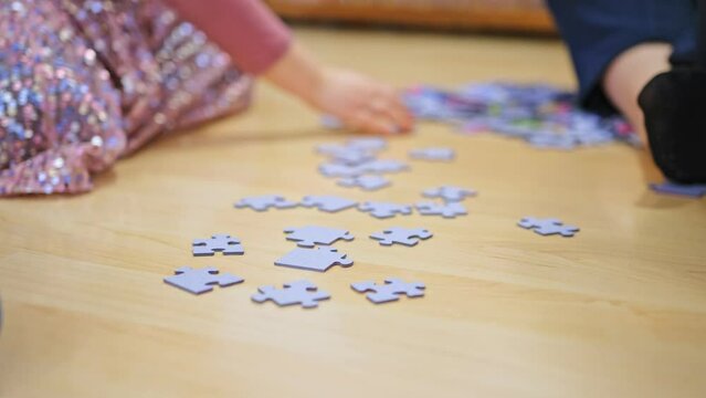 Caucasian Preschooler Girl Playing With Jigsaw Puzzle Pieces Scattered on a Floor