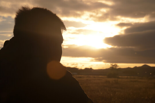 Silhouette of a man against a golden sunset sky in the countryside