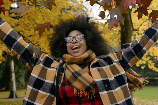 Joyful black young woman celebrating autumn in a park with vibrant fall foliage
