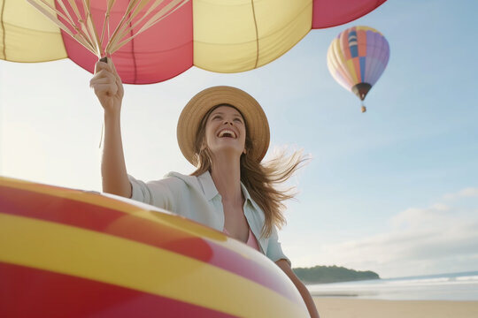 Woman with colorful parasol smiling on sunny beach with hot air balloons in the sky