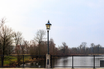 A street lamp in the centre of the bridge over the Wertach river on an iron railing on a cloudy day...