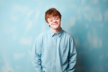 Boy with Down syndrome poses for a photo in front of a blue wall