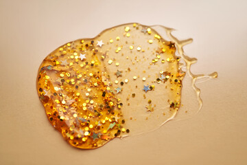 Cosmetic gel with glitter on a beige background.
