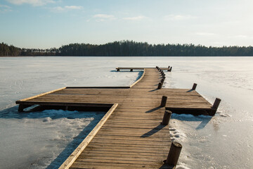 Wooden footbridge in Ratnieku frozen lake in early spring in March in Ratnieki in Latvia