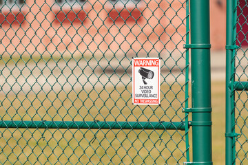 warning sign 24hr surveillance on a fence copy space
