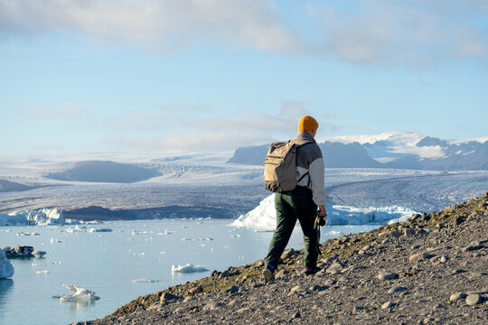 Young explorer with backpack,camera at glacier lagoon.Floating iceberg