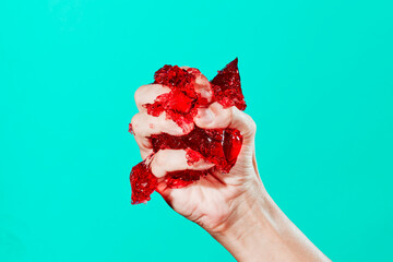 man is squeezing a bunch of red jelly in his hand