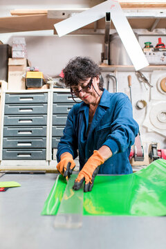 Smiling mature worker cutting vinyl stickers at factory