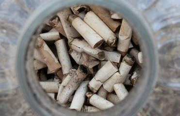 close up of a pile of cigarette butts inside a plastic can. Pollution concept