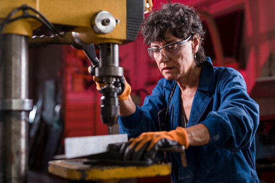 Senior woman working with industrial drill at workshop