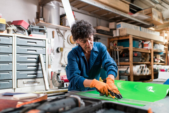 Focused mature worker cutting materials at factory