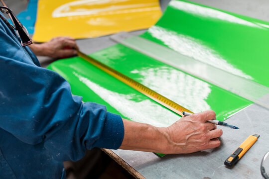 Worker hands measuring vinyl on workshop table