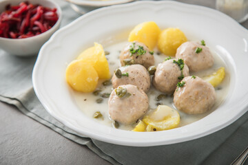 Königsberger Klopse mit Kapern, Salzkartoffeln und Rote Beete Salat auf tiefer Teller und grauen...