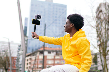 Smiling african man in yellow hoodie interacts with followers.