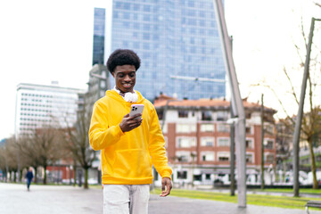African youth with a bright smile using phone in a city setting.