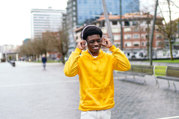 Joyful african young man feeling the music with his headphones outdoors in the city.