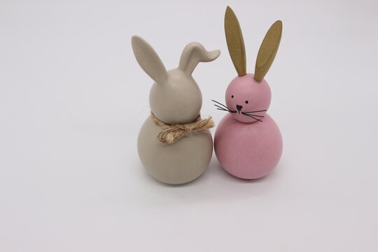 An image of two toy hares in gray and pink on a light background.