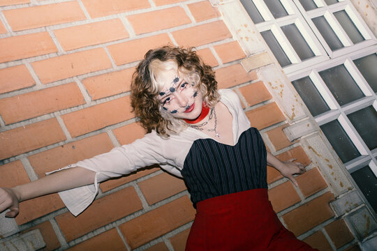 woman stands on brick wall next to window