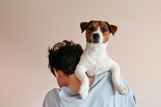 Anonymous boy holding dog on his shoulders.