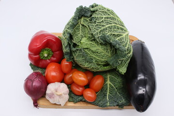 Image of a vegetable salad set on a cutting board, cabbage, tomato, and garlic, on a light background.