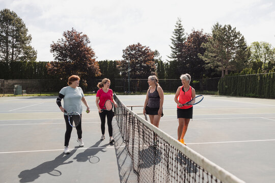 Four women high fiving and congratulating each other after fun tennis.