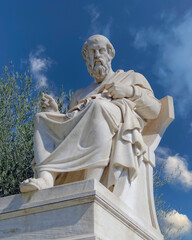 Fototapeta premium Plato, the ancient Greek philosopher marble statue, sitting and in deep thought under partly cloudy sky. Travel to Athens, Greece.