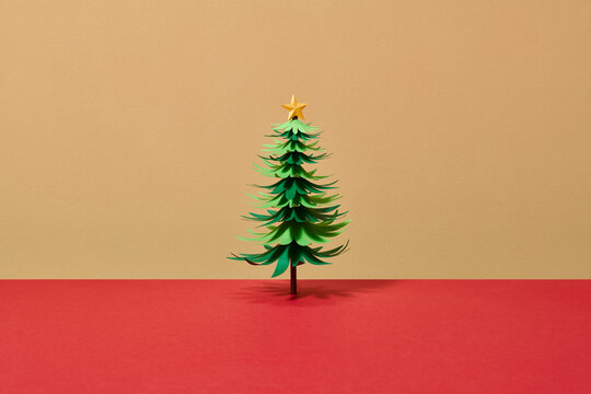Green origami christmas tree isolated on beige and red background