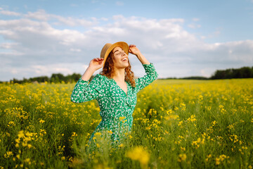 Naklejka na ściany i meble Happy woman walking in flowering field. Fashion, beauty concept. Summer landscape.
