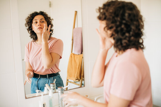Woman washing her face and looking in the mirror